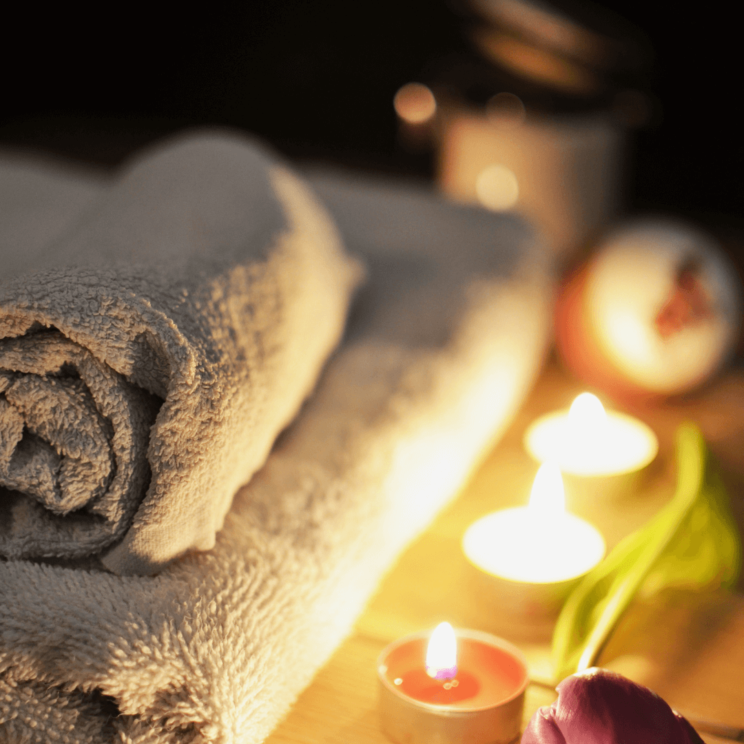 Massage thérapeutique et détente à Chavornay Des serviettes enroulées et des bougies allumées créant une atmosphère apaisante, symbolisant les services de massage détente et thérapeutique offerts à Chavornay