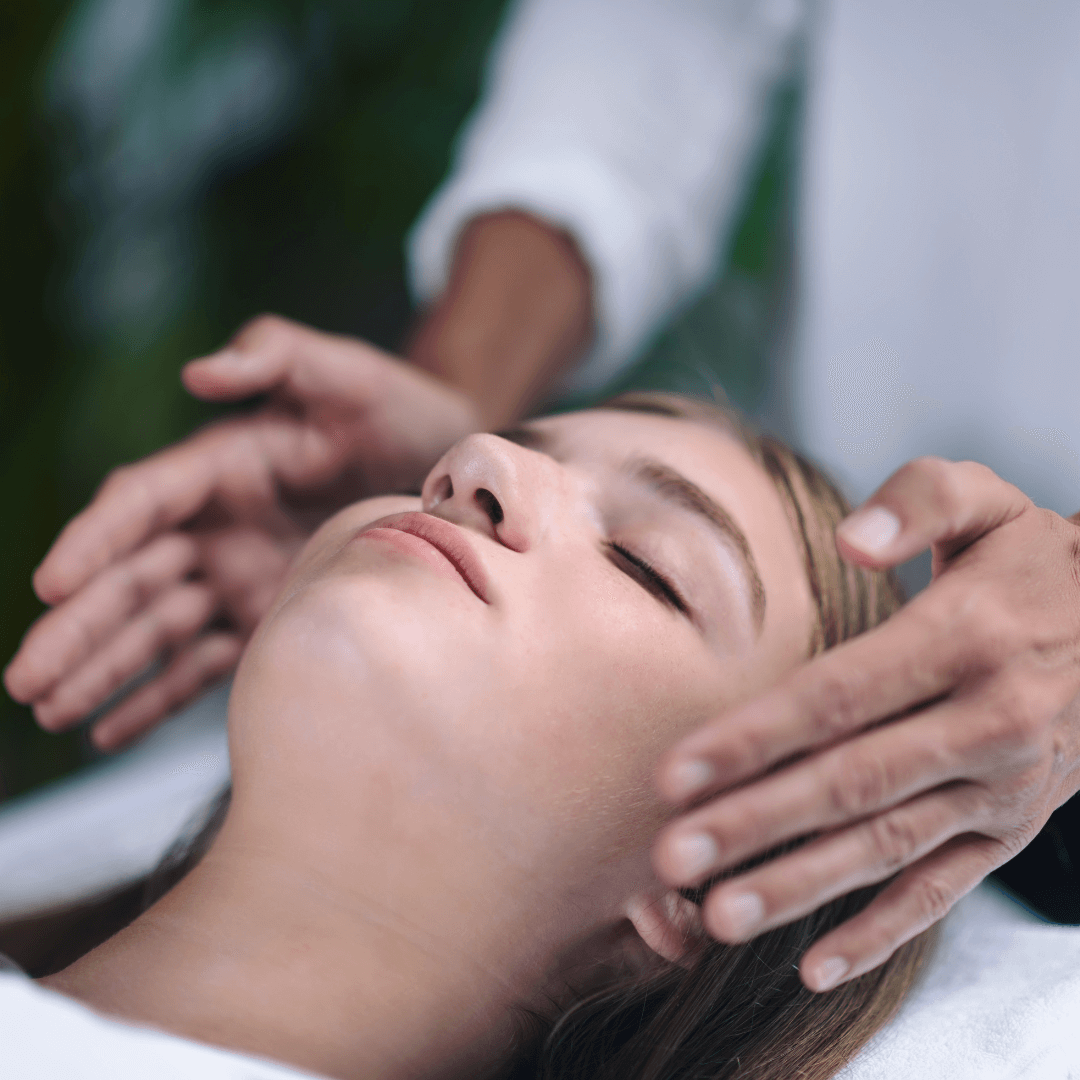 Séance de Reiki à Cossonay Un praticien de Reiki plaçant délicatement ses mains près de la tête d'une patiente allongée et détendue, illustrant une séance de soins énergétiques Reiki à Cossonay.