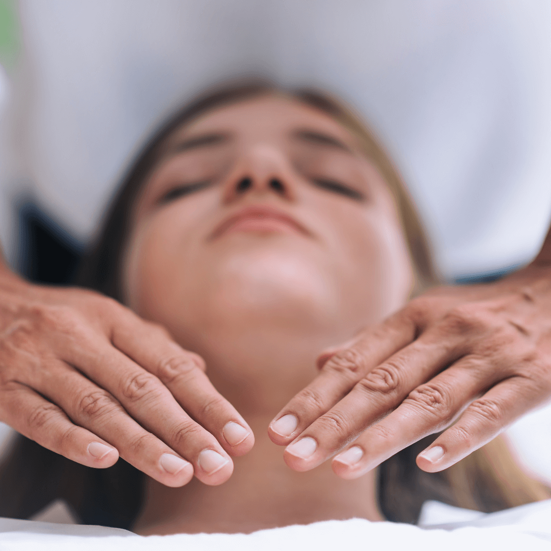 Séance de Reiki à La Sarraz Un praticien de Reiki plaçant délicatement ses mains près du cou d'une patiente allongée et détendue, illustrant une séance de soins énergétiques Reiki à La Sarraz.