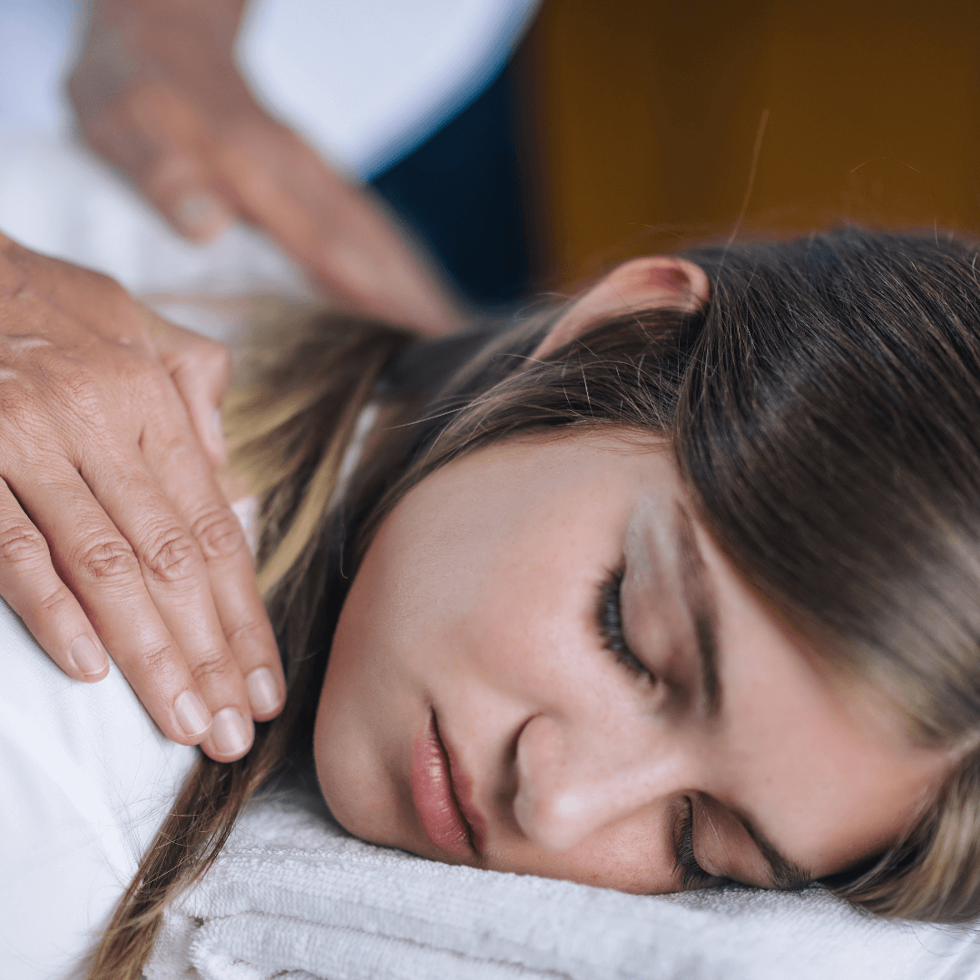 Séance de Reiki à Orbe Un praticien de Reiki plaçant délicatement ses mains sur le dos d'une patiente allongée et détendue, illustrant une séance de soins énergétiques Reiki à Orbe.