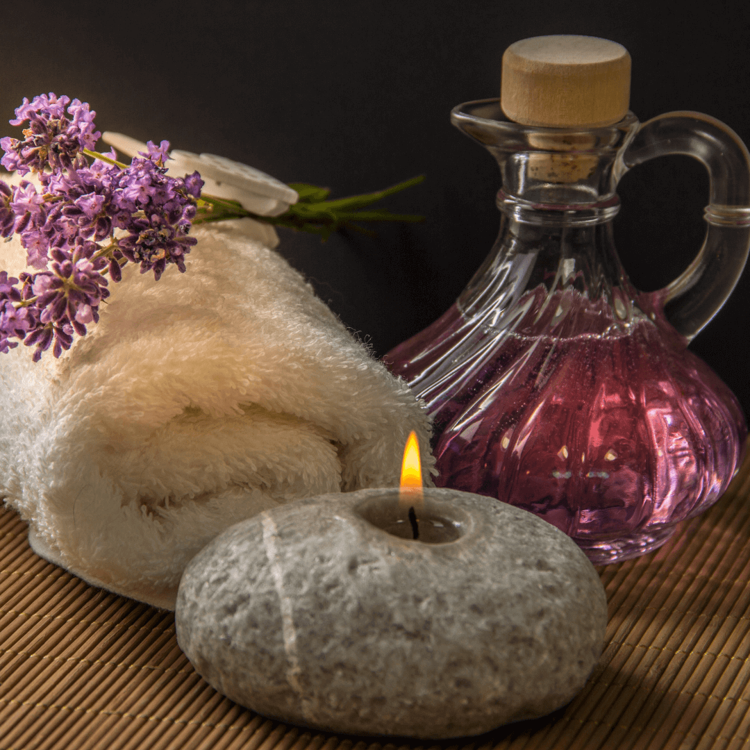 Massage thérapeutique et détente à Orbe Une scène de relaxation avec une serviette blanche roulée, un bouquet de lavande, une bougie allumée et une bouteille d'huile, illustrant les services de massage thérapeutique et détente disponibles à Orbe.